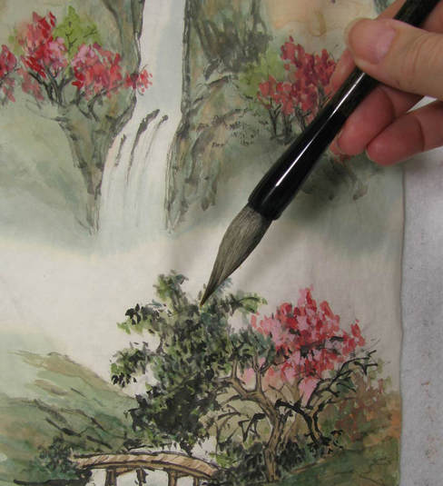 Paint brush hovering over painting